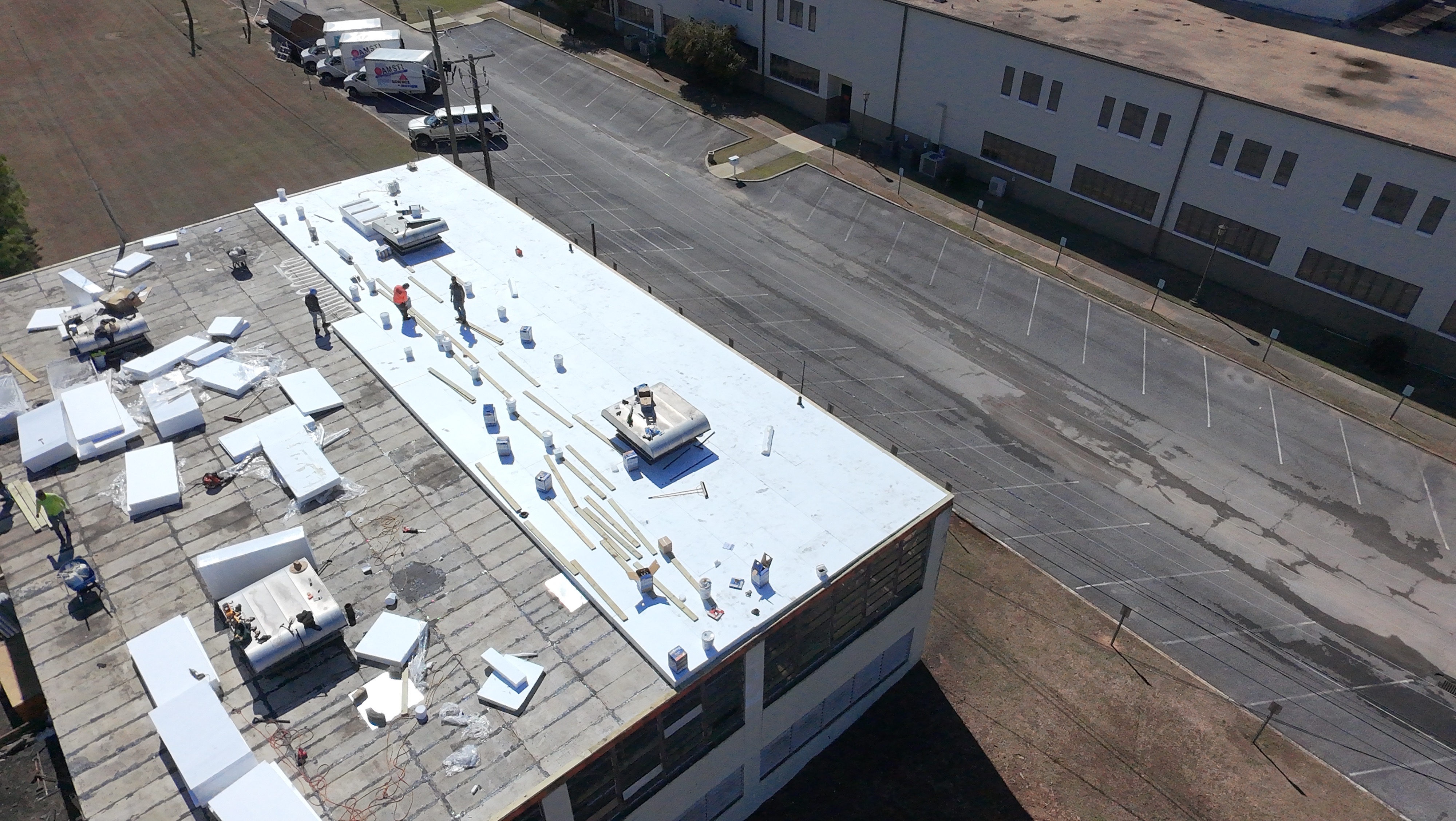 Aerial view of weathered built-up roof before replacement, showing extensive granule loss and damage