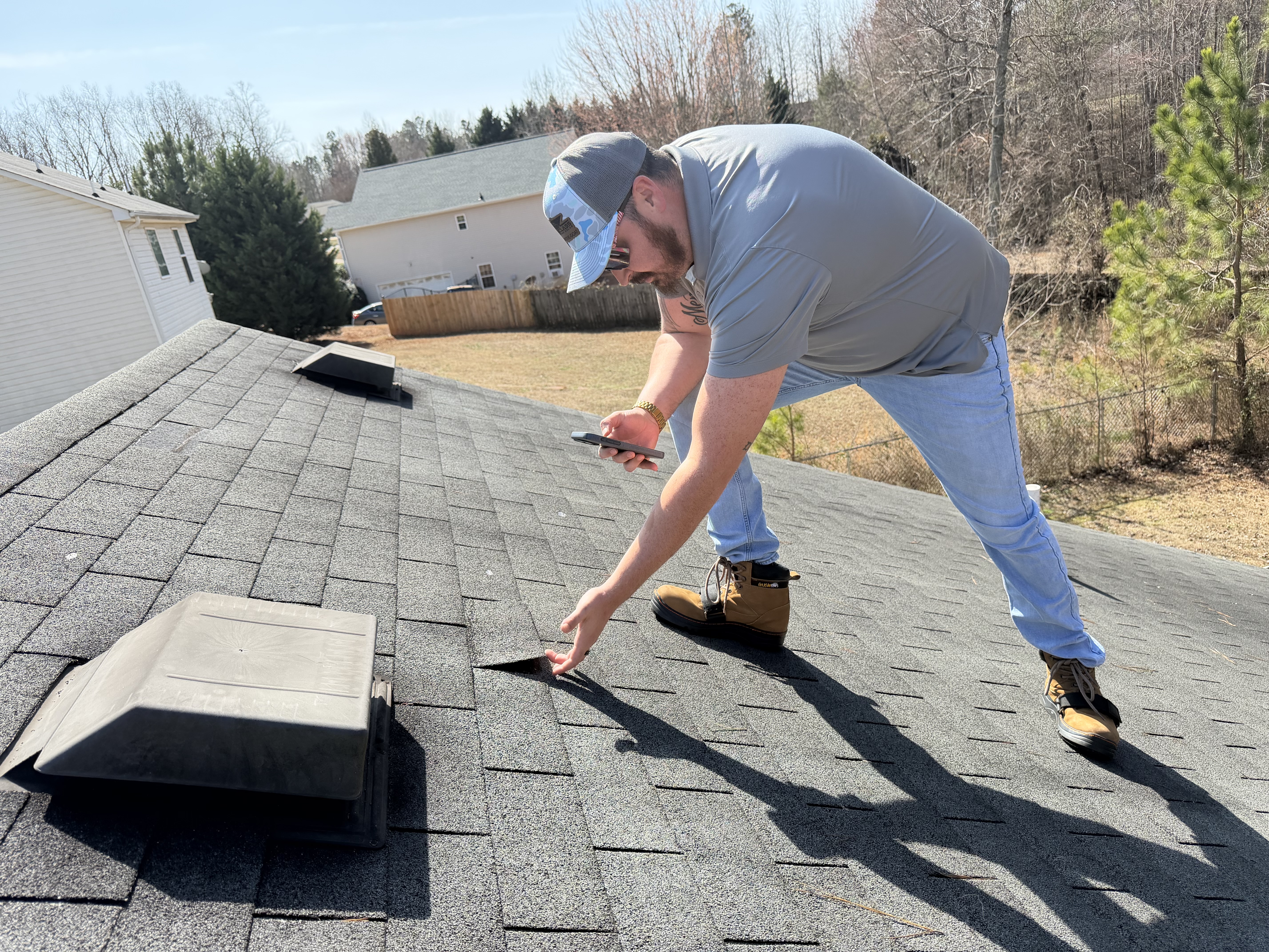 First Class Roofing inspector documenting shingle damage on a residential roof in Alabama and Georgia