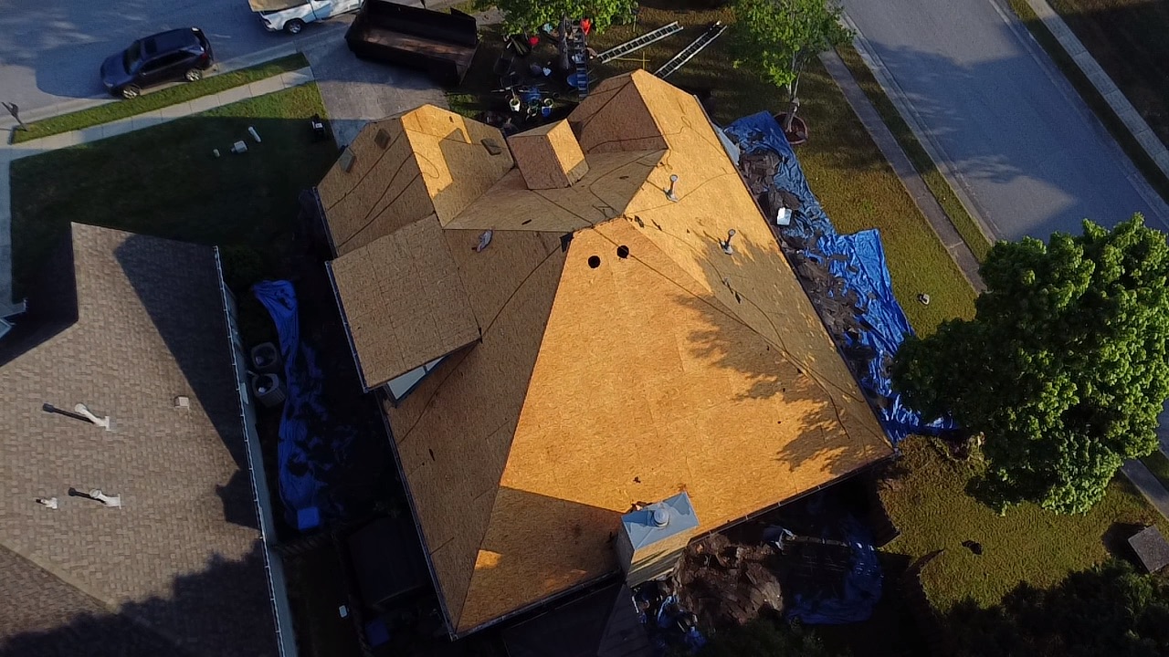 Tear-off complete on Trussville Alabama residential roof showing exposed OSB decking and protective tarps