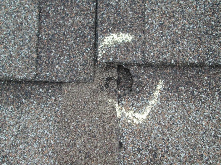 Close aerial of storm-damaged shingles documented by First Class Roofing