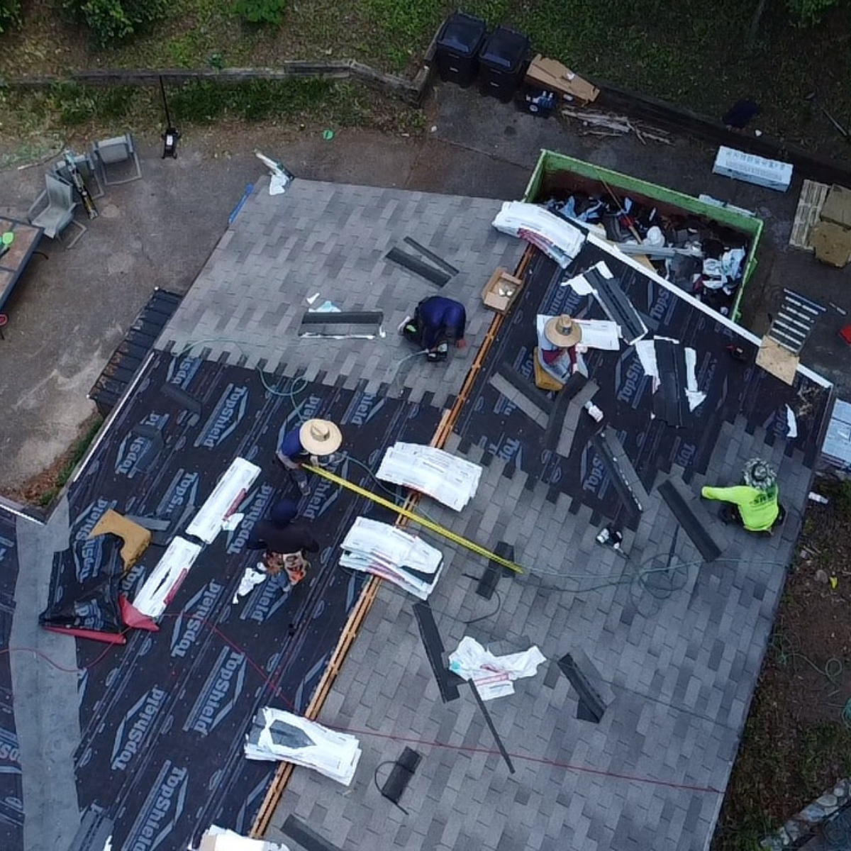 Aerial view of an active First Class Roofing job site with materials staged on the roof